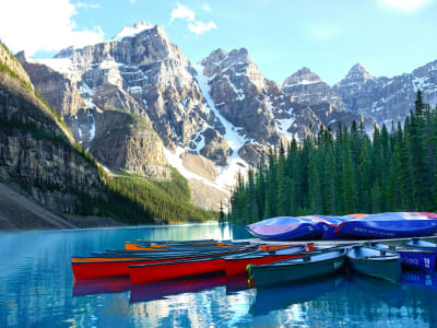 Red canoes on turquoise Moraine Lake with mountain backdrop, Banff National Park