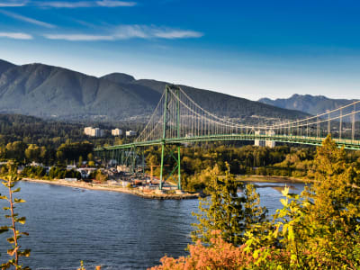 Lions Gate Bridge spanning the Burrard Inlet surrounded by Stanley Park autumn forest and North Shore mountains, Vancouver BC
