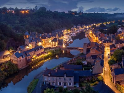 Aerial night view of a charming illuminated French village with a medieval bridge reflected in the river