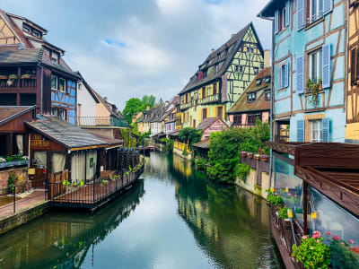 Tranquil canal in Colmar's Petite Venise with a wooden boat and reflections of half-timbered houses, Alsace France