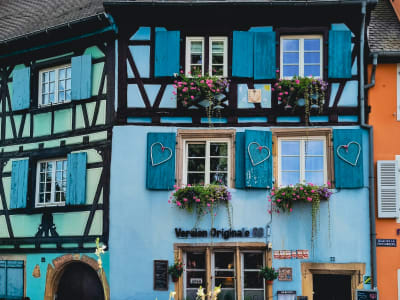 Bright blue half-timbered house facade with colorful shutters and flower boxes in Colmar, Alsace France