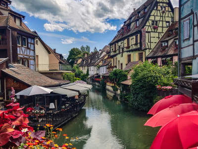 Canal in La Petite France Strasbourg with red parasols, blooming flowers and half-timbered houses in summer