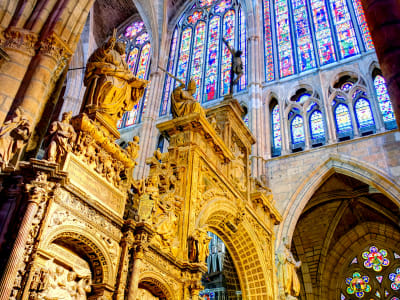 Golden interior of Reims Cathedral with ornate stained glass windows illuminating the Gothic stone columns, France