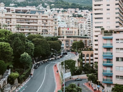 Winding street in Monaco with Mediterranean-style apartment buildings and lush greenery on the hillside