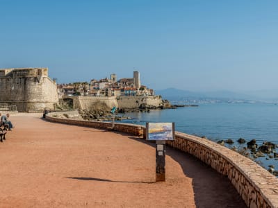 Scenic coastal walkway along the medieval ramparts of Antibes with the Mediterranean Sea and mountains in the background