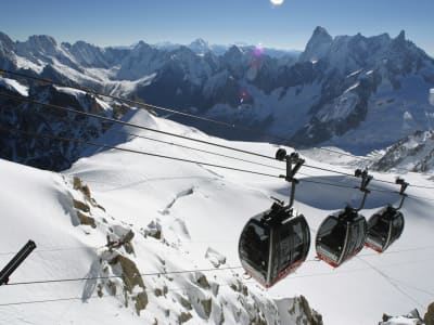 Cable car gondolas ascending over a snow-covered alpine landscape in Chamonix, French Alps France