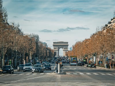 Street-level view of the Champs-Élysées with plane trees, traffic and the Arc de Triomphe, Paris France