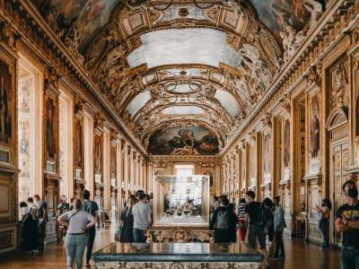 The opulent Grande Galerie of the Louvre Museum with gilded ceilings and visitors admiring paintings, Paris France