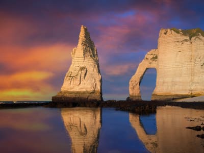 The Aiguille needle and Porte d'Aval arch at Étretat reflected in wet sand at sunset, Normandy France