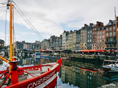 Honfleur harbour with a red sailing boat and the iconic row of tall narrow houses, Normandy France