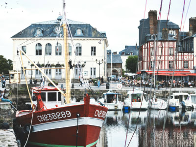 Red fishing boat moored in Honfleur's Vieux Bassin with colorful Norman facades reflected in the water, France