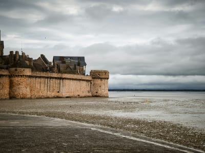 The medieval defensive walls of Mont-Saint-Michel rising from the exposed tidal flats at low tide, Normandy France