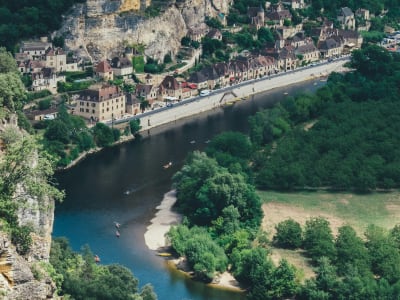 Aerial view of Beynac-et-Cazenac with its medieval castle above the Dordogne River and kayakers below, Périgord France