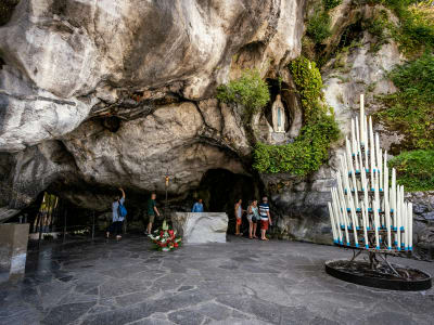 Pilgrims praying at the Massabielle Grotto with candles and the statue of the Virgin Mary, Lourdes France