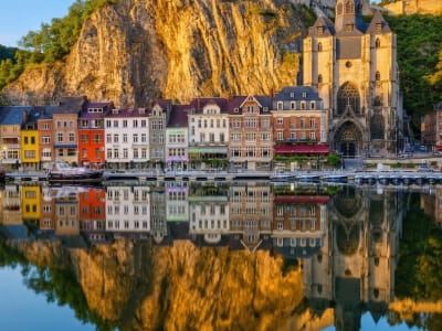 Vibrant coloured house facades and Gothic church reflected in the still waters of the Meuse river in Dinant, Belgium