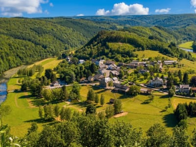 Aerial view of a small village nestled in the lush green hills and forested valleys of the Belgian Ardennes