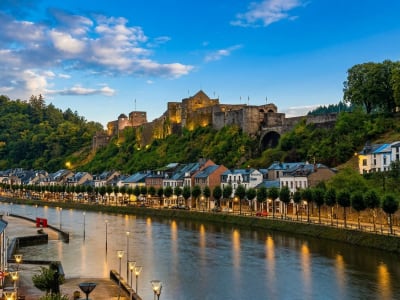 The medieval Castle of Bouillon rising above the Semois river and town at golden hour, Belgian Ardennes