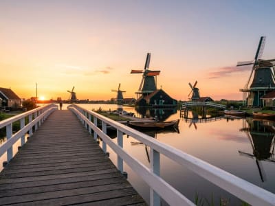 Traditional Dutch windmills at Zaanse Schans silhouetted against a golden sunset reflected in the Zaan river, Netherlands
