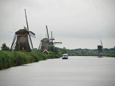 Historic windmills lining the canal at Kinderdijk UNESCO World Heritage Site with a tour boat, Netherlands