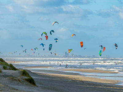 Colourful kitesurfers riding the waves on the wide Scheveningen North Sea beach, The Hague, Netherlands