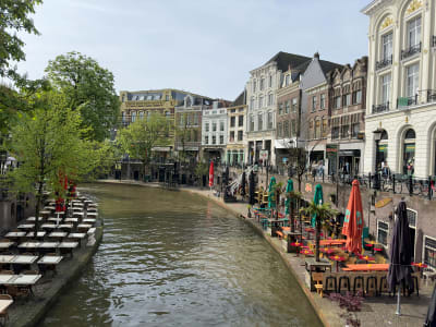 Busy Oudegracht canal with waterfront terrace cafés and historic buildings in Utrecht city centre, Netherlands