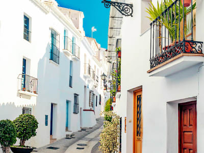 Charming white-washed alley with colourful flower balconies and terracotta pots in an Andalusian village, Spain