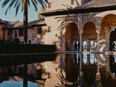 The Nasrid Palaces courtyard with arched arcades reflected in the still water pool at the Alhambra, Granada, Spain