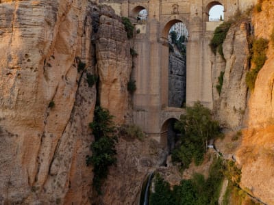 The Puente Nuevo bridge illuminated at golden hour towering above the El Tajo gorge in Ronda, Spain