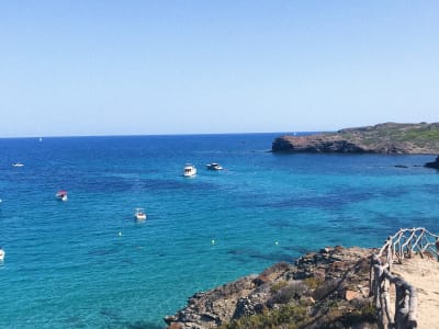 Rocky coastline with crystal clear blue water and boats in Menorca Balearic Islands
