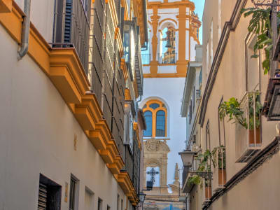 Narrow historic alley in Palma de Mallorca old town with golden stone buildings and blue sky