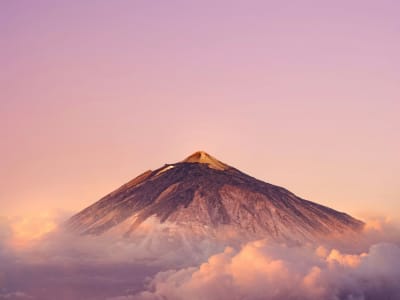 Mount Teide volcano Tenerife at sunrise with pink sky and clouds below summit Canary Islands