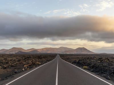 Straight road through black lava desert at sunset in Timanfaya National Park Lanzarote Spain