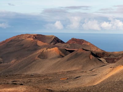 Red volcanic crater cone in Timanfaya National Park Lanzarote with blue sky Canary Islands Spain