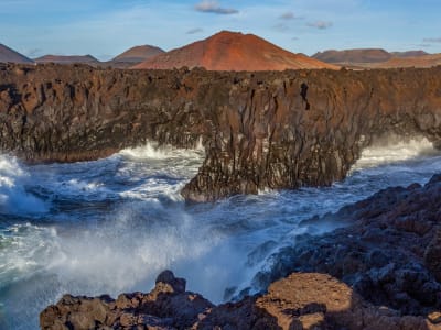 Atlantic waves crashing against black volcanic rock arch on Lanzarote coast near Timanfaya Spain