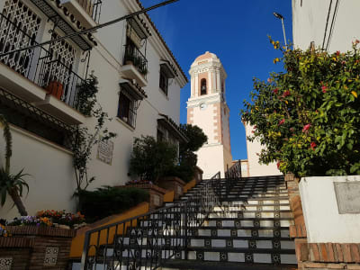 Narrow staircase in Estepona old town with church tower flower pots and whitewashed walls Spain