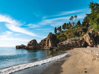 Secluded sandy beach with clear turquoise water and rocky cliffs near Nerja Andalusia Spain