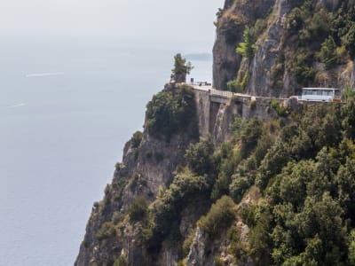 Winding coastal road carved into dramatic cliffs along Amalfi Coast with sea below Italy