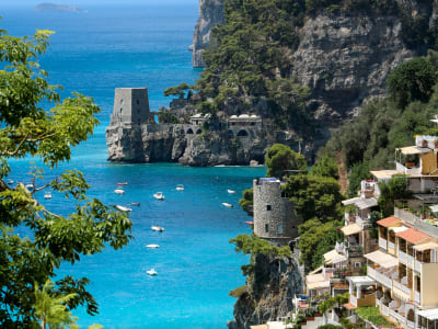 Amalfi town with medieval tower boats and colorful hillside houses along turquoise coast Italy
