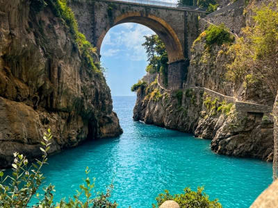 Rocky gorge with stone arch bridge and turquoise sea at Praiano Amalfi Coast Italy