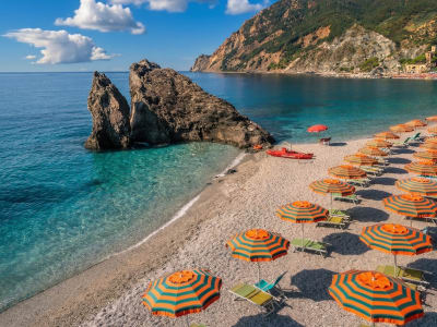 Monterosso al Mare beach with orange parasols rock arch and turquoise water Cinque Terre Italy