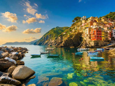 Riomaggiore Cinque Terre at dusk with golden sky colorful houses and rocky sea wall Italy