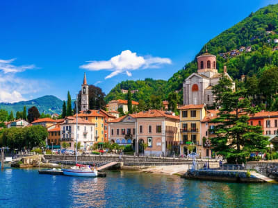 Lake Como with traditional lakeside villas and green mountains reflected in calm water Italy