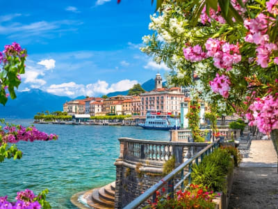Lake Como terrace with pink wisteria blooms overlooking turquoise lake and mountain backdrop Italy