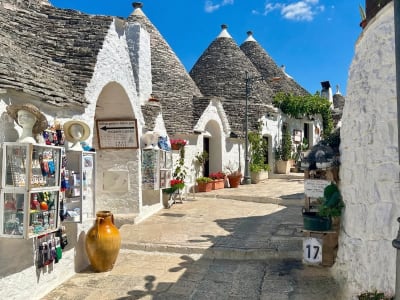 Whitewashed trulli houses along a cobblestone street with souvenir shops in Alberobello