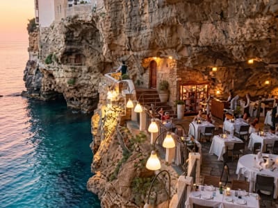 Romantic cave restaurant with warm lantern lighting and elegant dining tables in Polignano a Mare