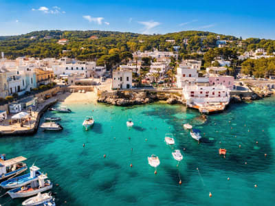 Whitewashed coastal town with fishing boats in a sheltered turquoise bay in Puglia, southern Italy