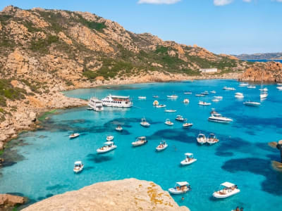 Aerial view of luxury yachts and boats anchored in a turquoise bay along the rocky Costa Smeralda coastline