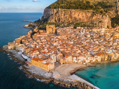 Aerial view of Cefalù old town with the Norman cathedral and terracotta rooftops beside the sea in Sicily