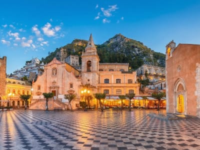 Piazza IX Aprile with the clock tower, church facade and panoramic terrace at sunset in Taormina, Sicily