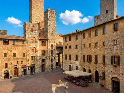 Piazza della Cisterna with medieval stone tower houses and a central well in San Gimignano, Tuscany, Italy